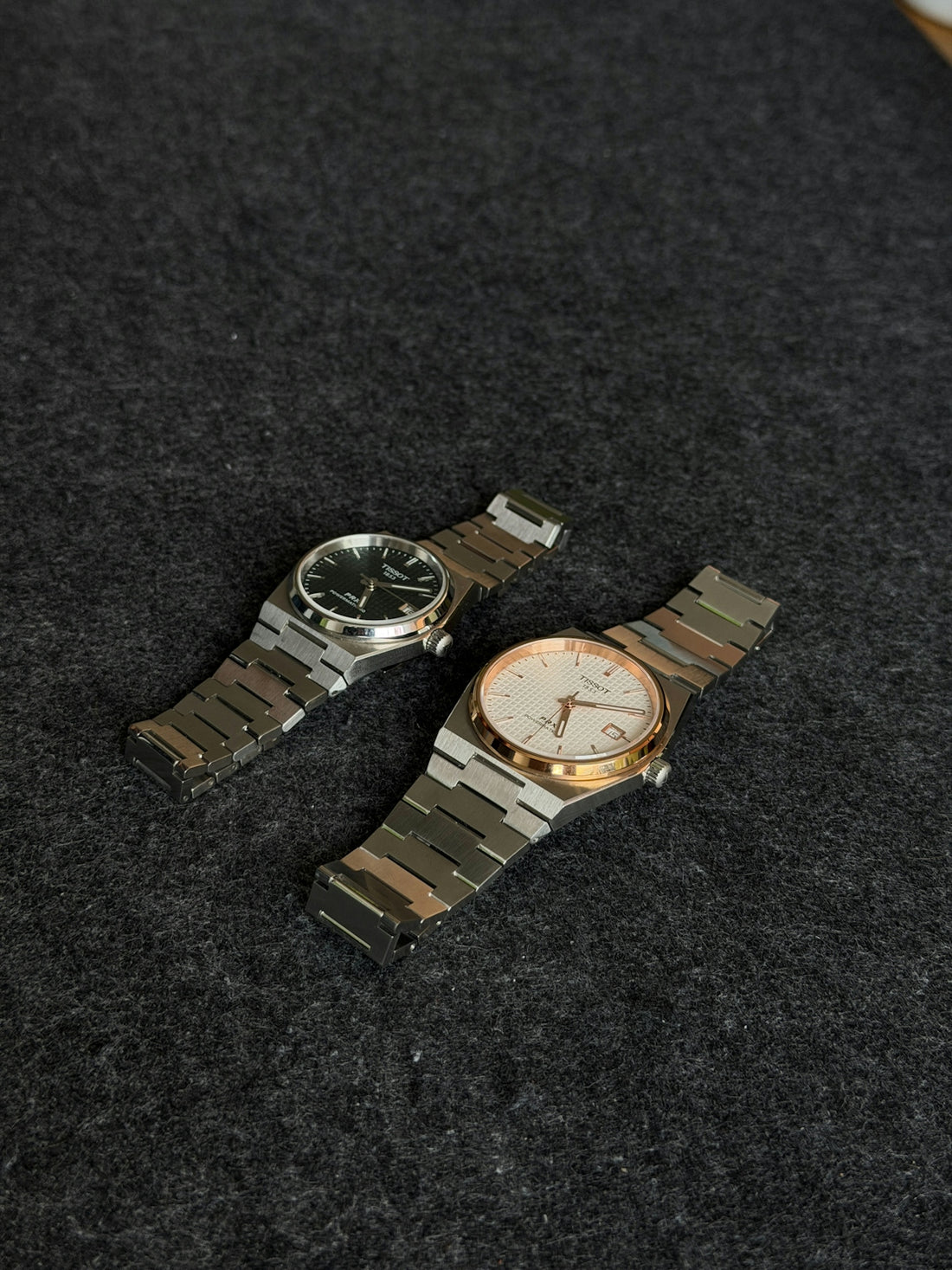 Two luxury watches on a dark textured surface