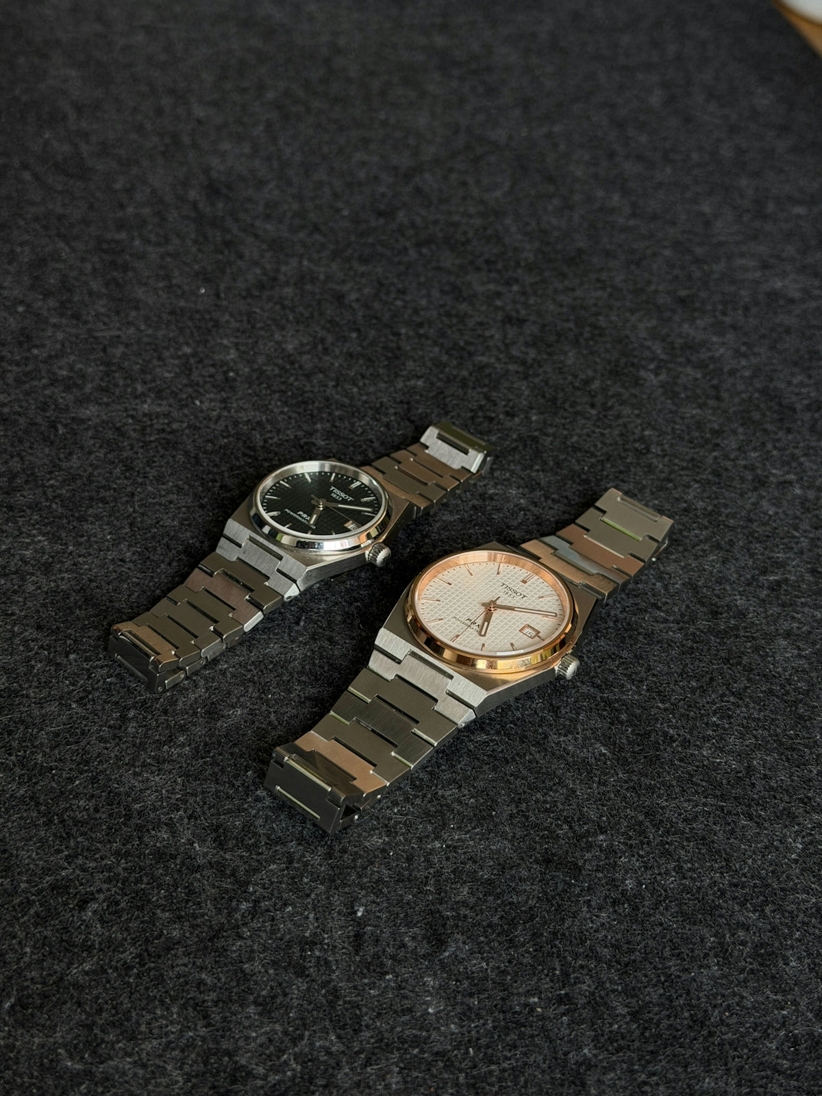 Two luxury watches on a dark textured surface