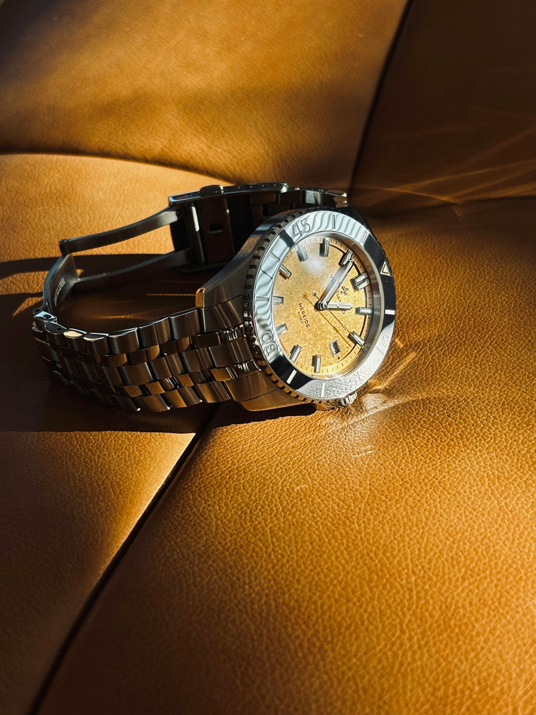 A stainless steel watch with a gold dial.