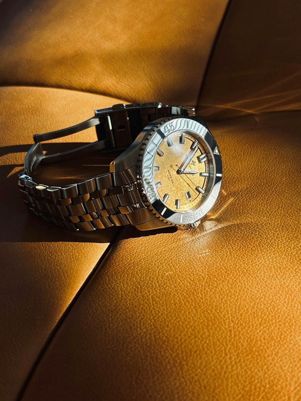 A stainless steel watch with a gold dial.