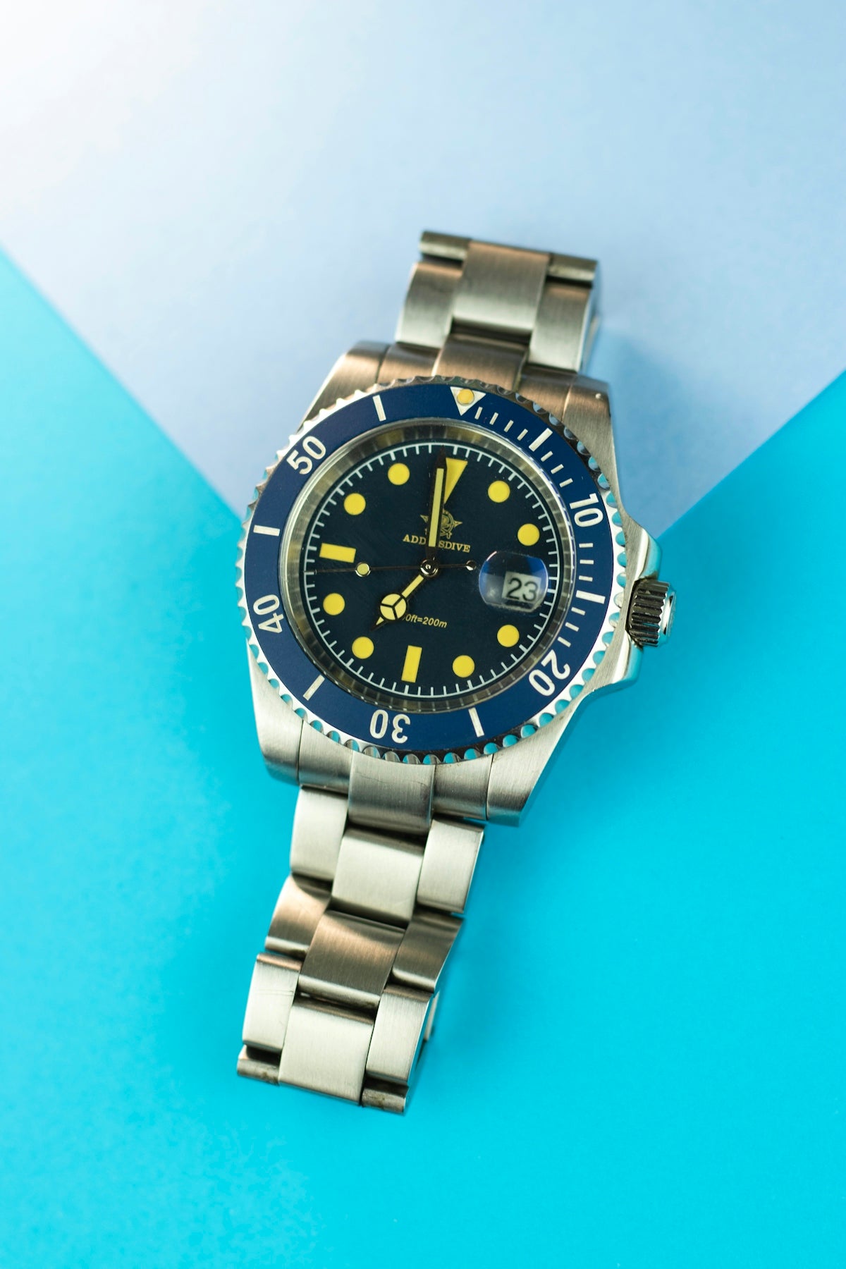 A stainless steel watch with a blue bezel