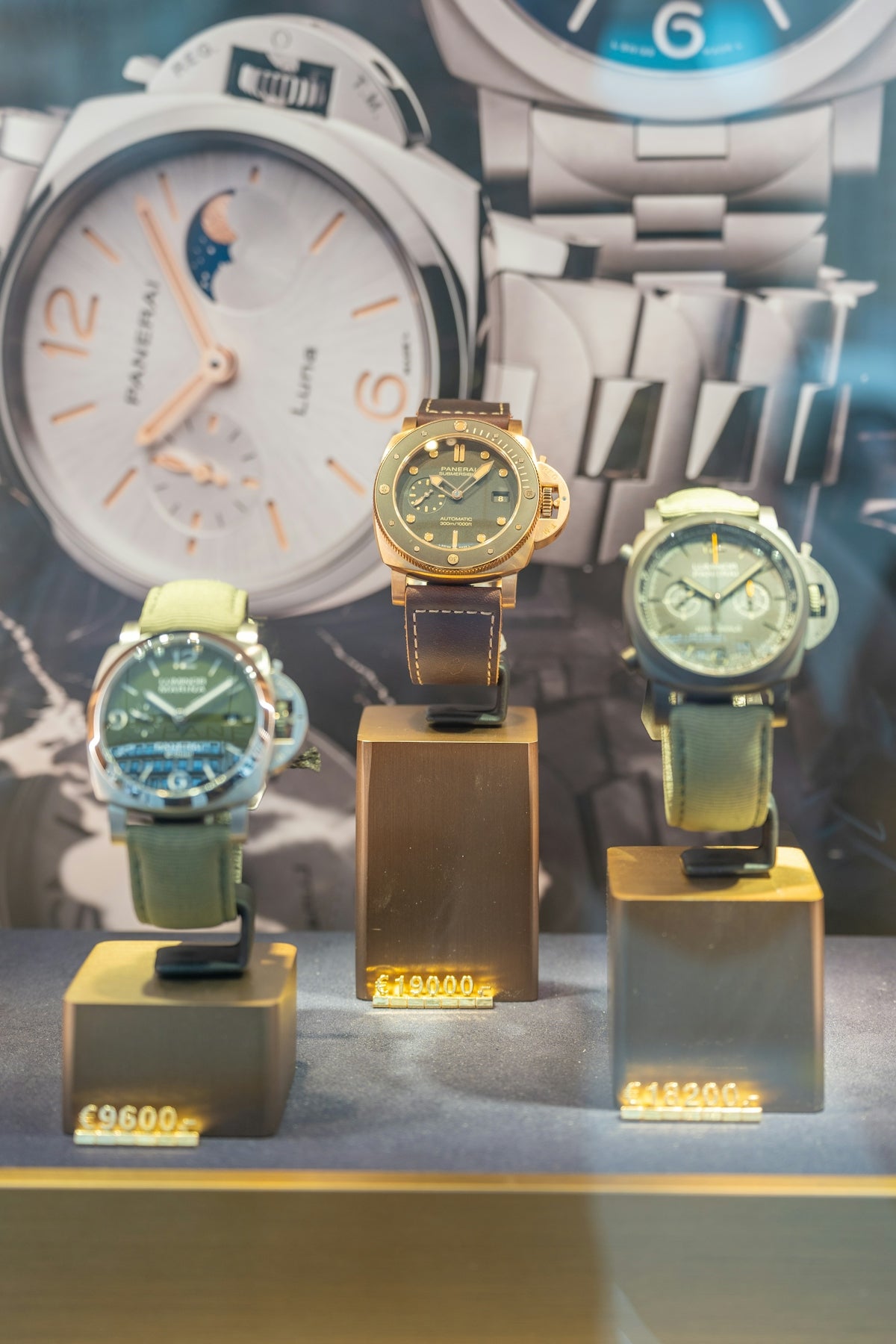 Three luxury watches displayed on stands