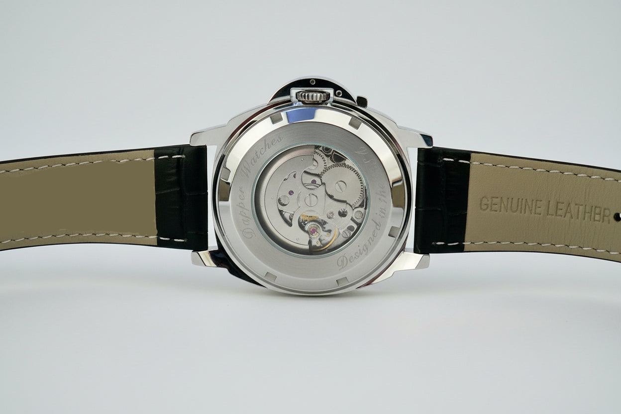 Close-up of a watch with a visible mechanical movement on a textured surface